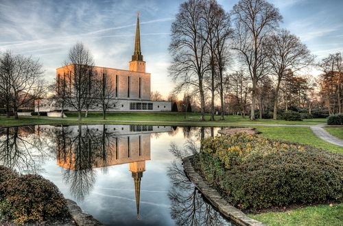 The London England Temple and bare trees on the temple ground, along with their reflection in the temple’s pond on a winter day.