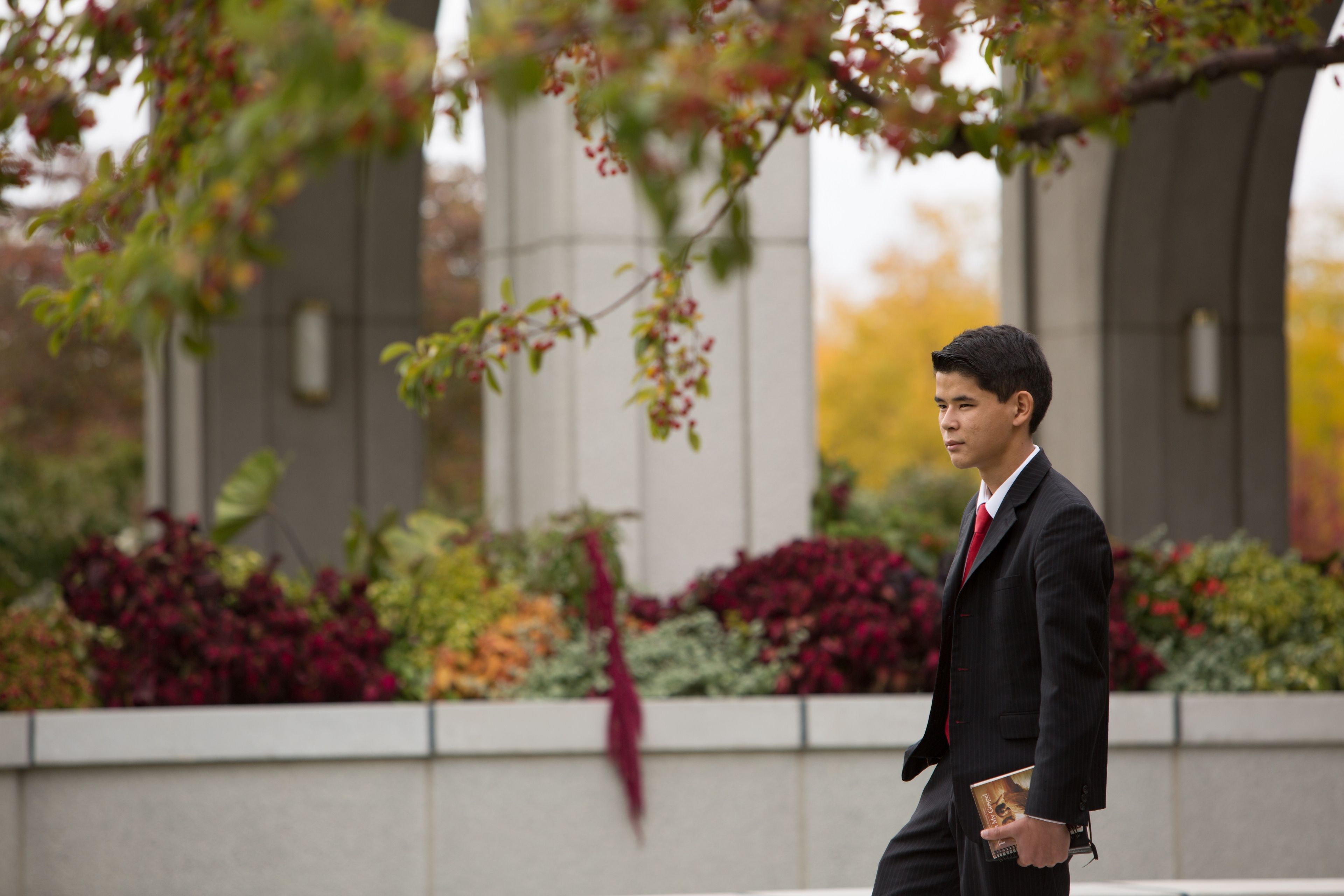 A young man in a suit walking by the Mount Timpanogos Utah Temple.