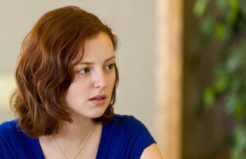 A young adult woman sitting at a table doing homework.