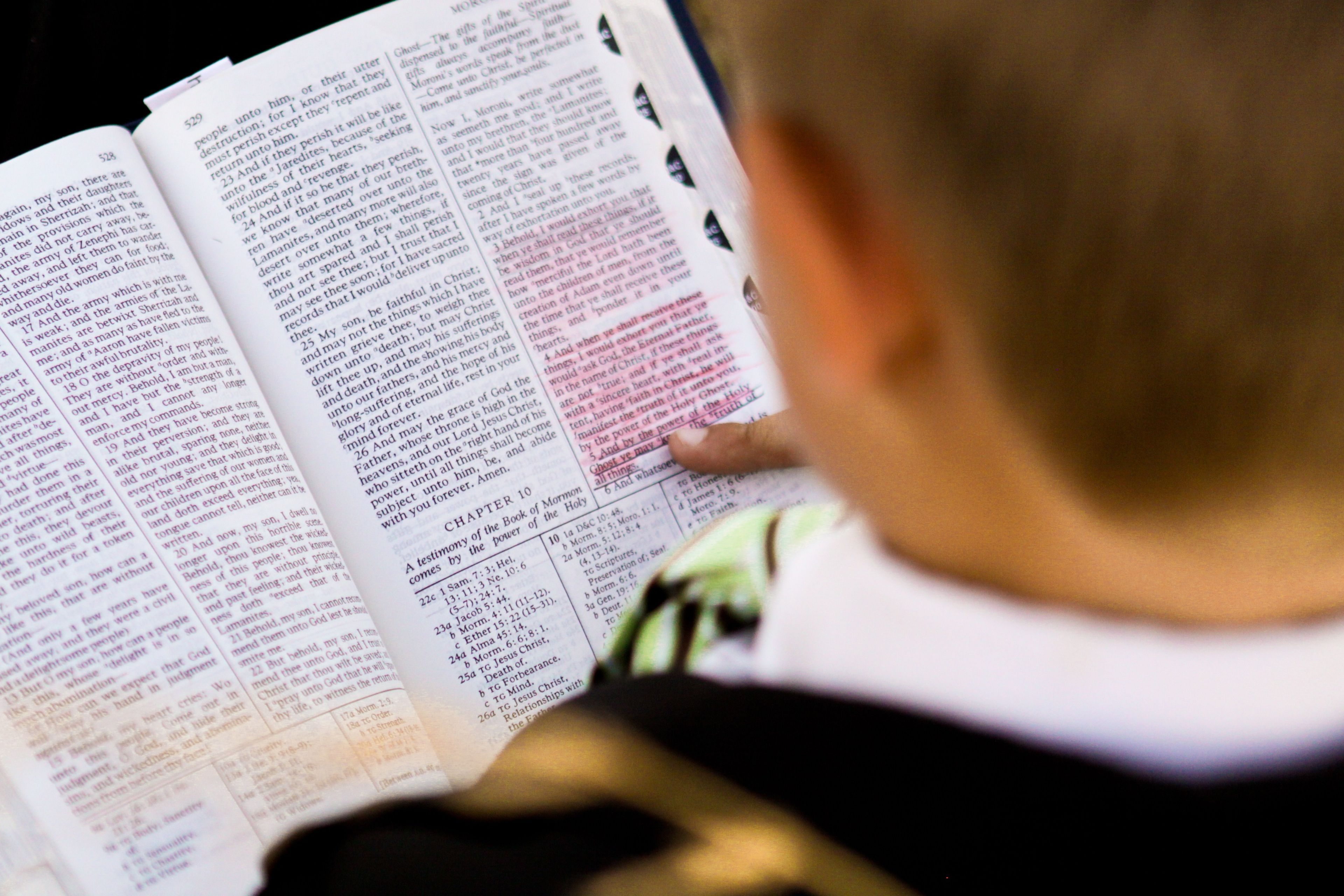 A boy holding open a copy of the Book of Mormon to Moroni chapter 10.