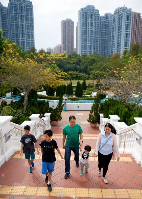 A series of images of a Chinese family going on a walk together. They can be seen walking through the city, a park, and enjoying their time together. Family consists of three sons, a mother and a father. One of the sons is being pushed in a stroller.