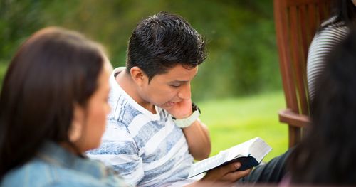 Young adults looking at the scriptures.