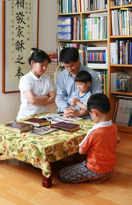 A photograph by Hyun-Gyu Lee of a family of four in Korea kneeling around a table for family prayer.