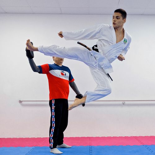 young man jumping and kicking in martial arts