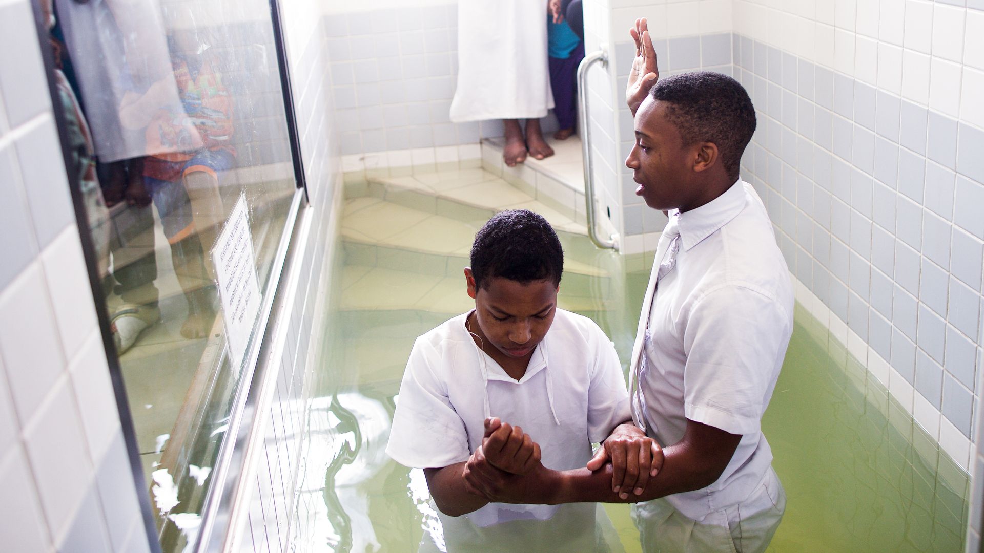A young man being baptized in a baptismal font in Madagascar.