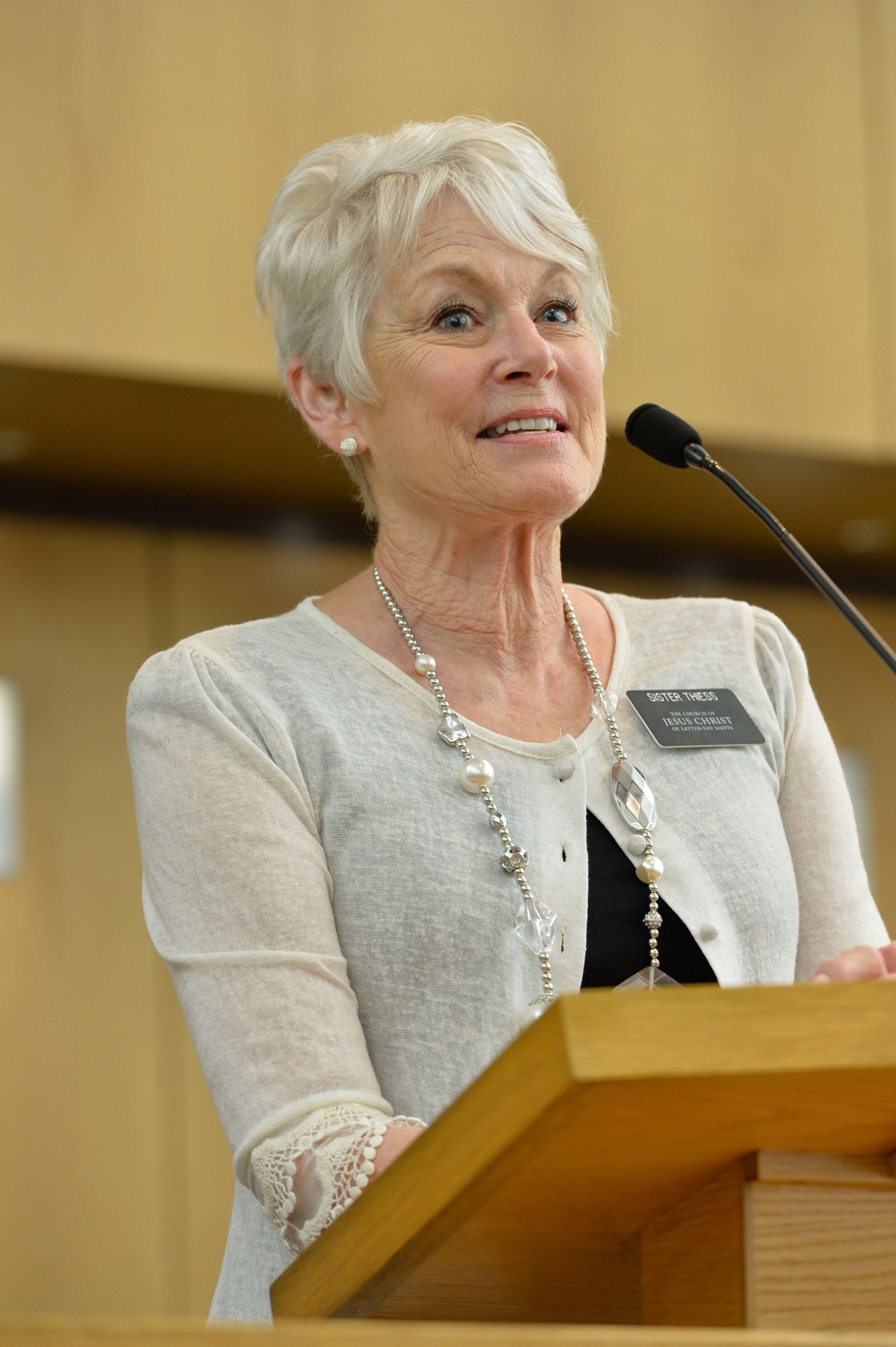 A senior missionary stands at a pulpit to speak to a congregation.