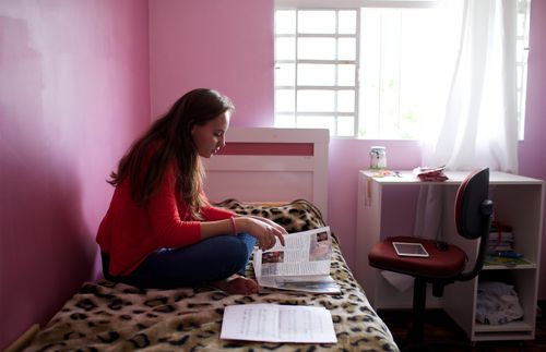 Una mujer sentada en su cama y leyendo una revista