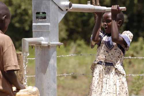 young girl pumping water in Africa