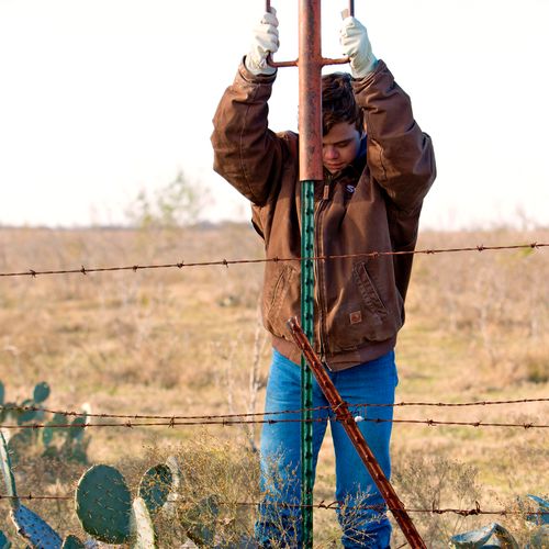 young man securing a fence post