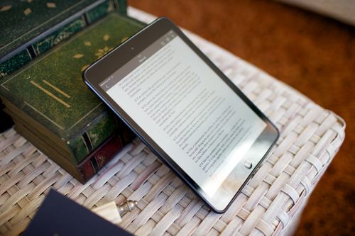 An iPad leaning against some green books, showing Alma 43 in Portuguese opened on the Gospel Library app.