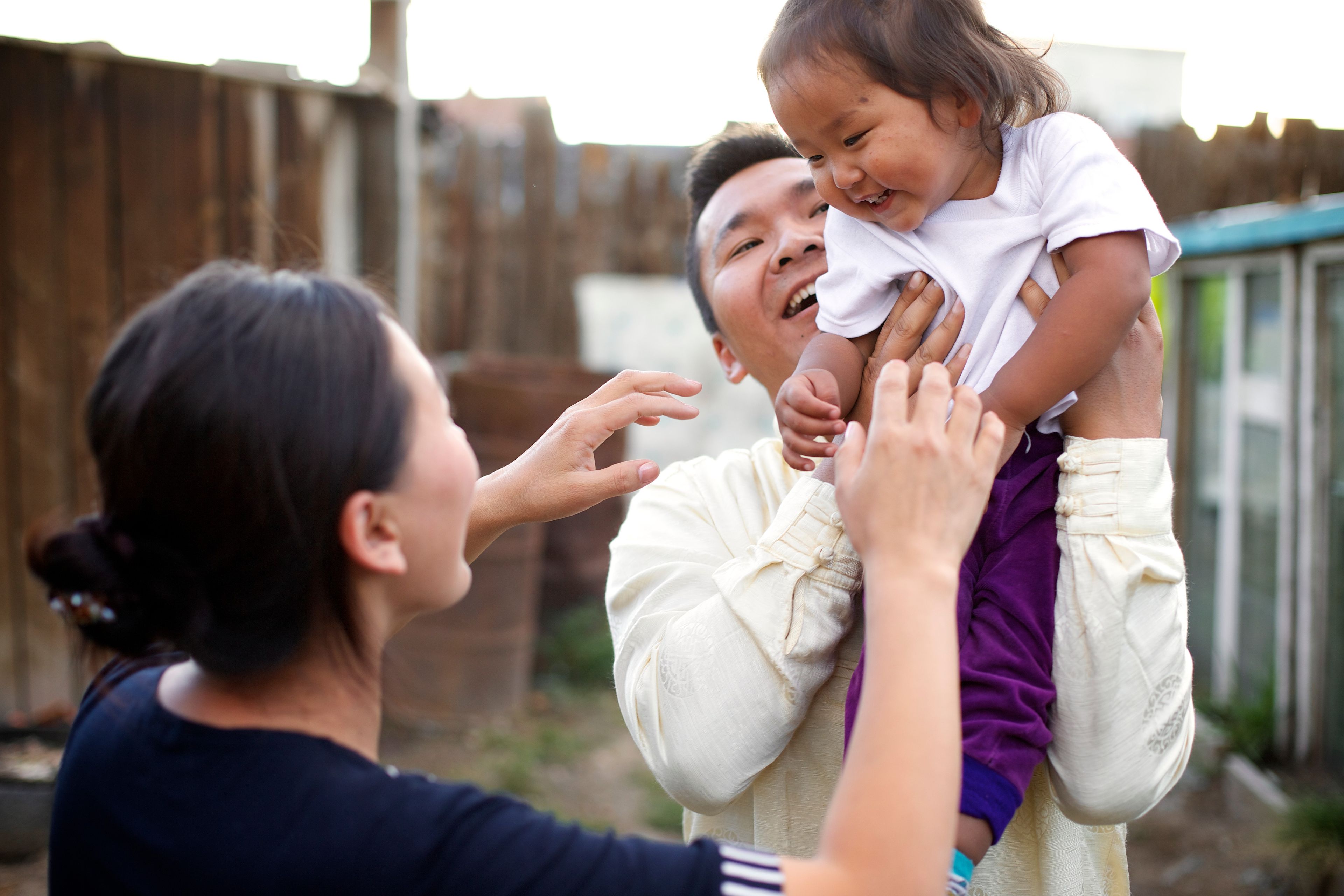 A mother and father play with their daughter.  