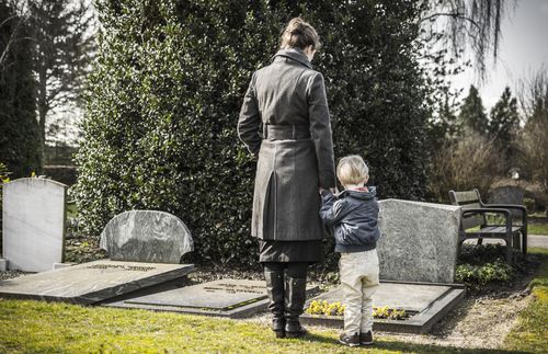 woman and boy standing in front of grave