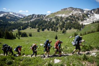 A group of scouts are all together. They are hiking on a path in the Grand Tetons. They appear to be backpacking.