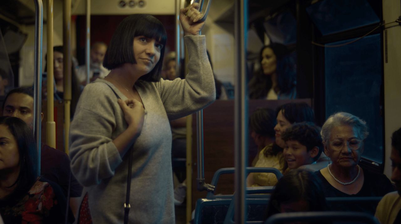 Uma mulher sorri levemente enquanto anda de metrô