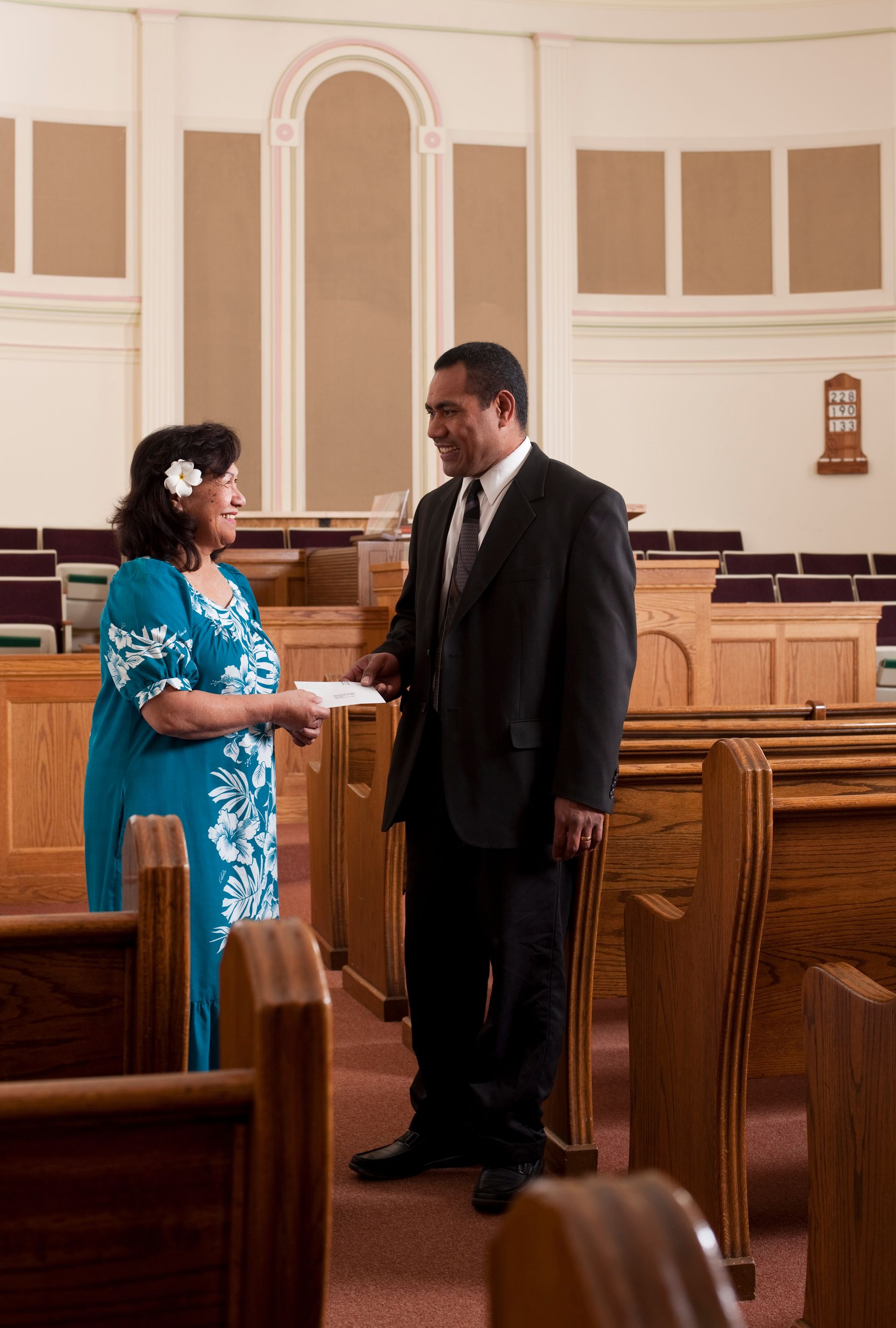 A woman giving a tithing envelope to her bishop.