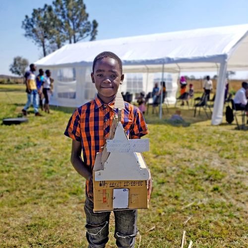 a young boy holding a temple model built of bricks and stones