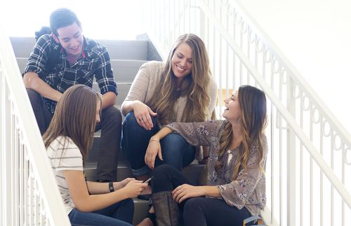 Young adults socializing while sitting on stairs.