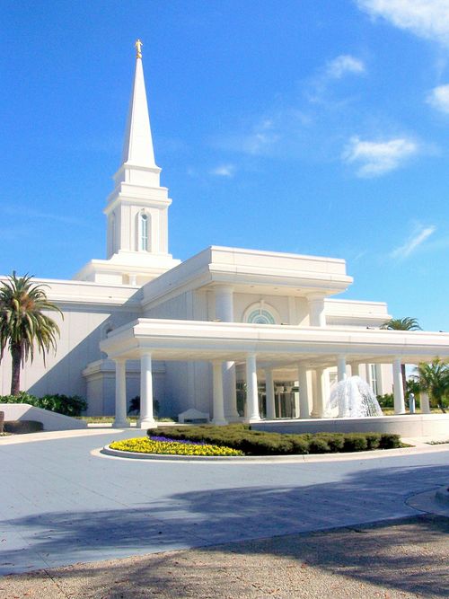 The front entrance to the Orlando Florida Temple on a sunny day, with a water fountain running near the door.