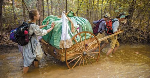 youth pulling handcart through mud