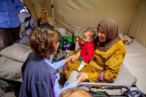 a woman comforts another woman and her child