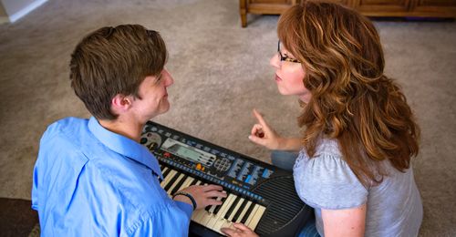 Young man at keyboard with mother