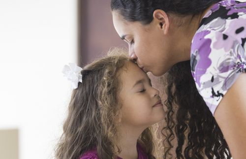 a mother giving her daughter a kiss