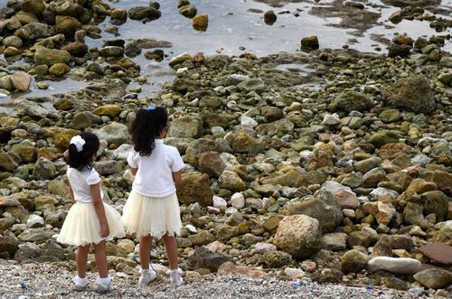 Two young girls stand on a rocky beach in Beirut, Lebanon.