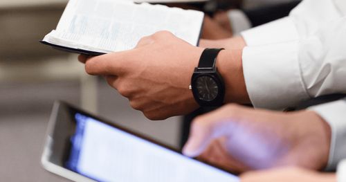 A row of hands holding scriptures or electronic devices.