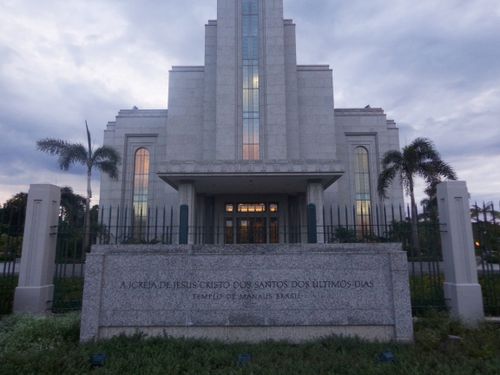 The name sign in front of the main entrance of the Manaus Brazil Temple at sunset, with the sunset reflecting in the windows.
