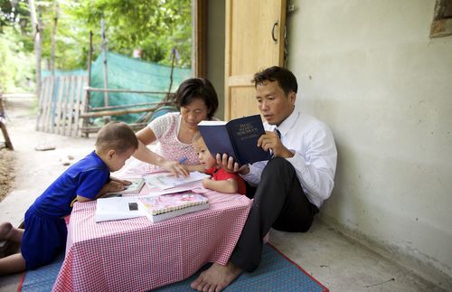 Parents and children reading from the scriptures.  Shot in Thailand.