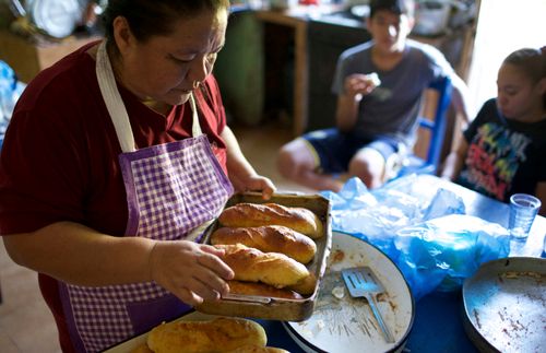 Eine Frau mit frisch gebackenem Brot; bei ihr sitzt ein Junge