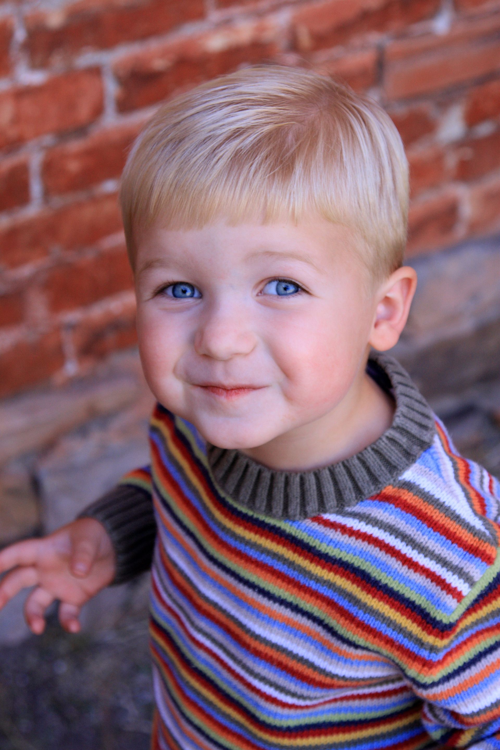 A portrait of a toddler boy wearing a striped sweater.