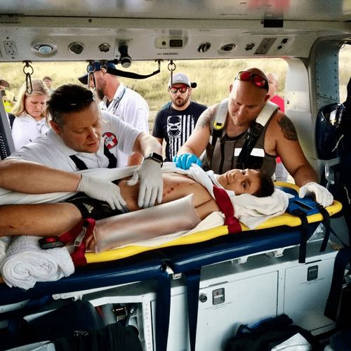 young man on stretcher with emergency medical technicians around him