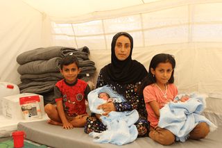 Mother and her children, including new twins, in a clean tent in Syria