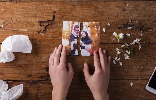 hands holding two torn pieces of a photograph