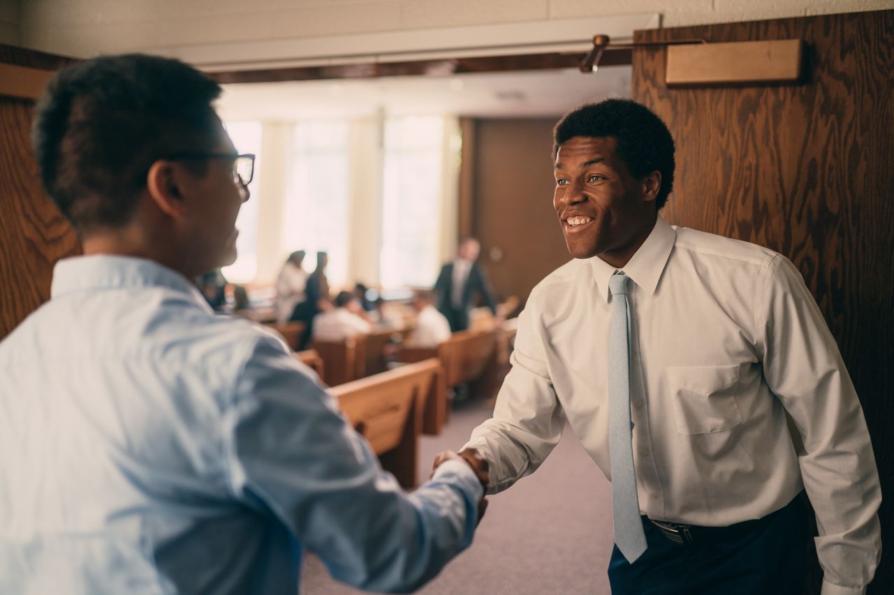 Men shake hands as they enter the chapel