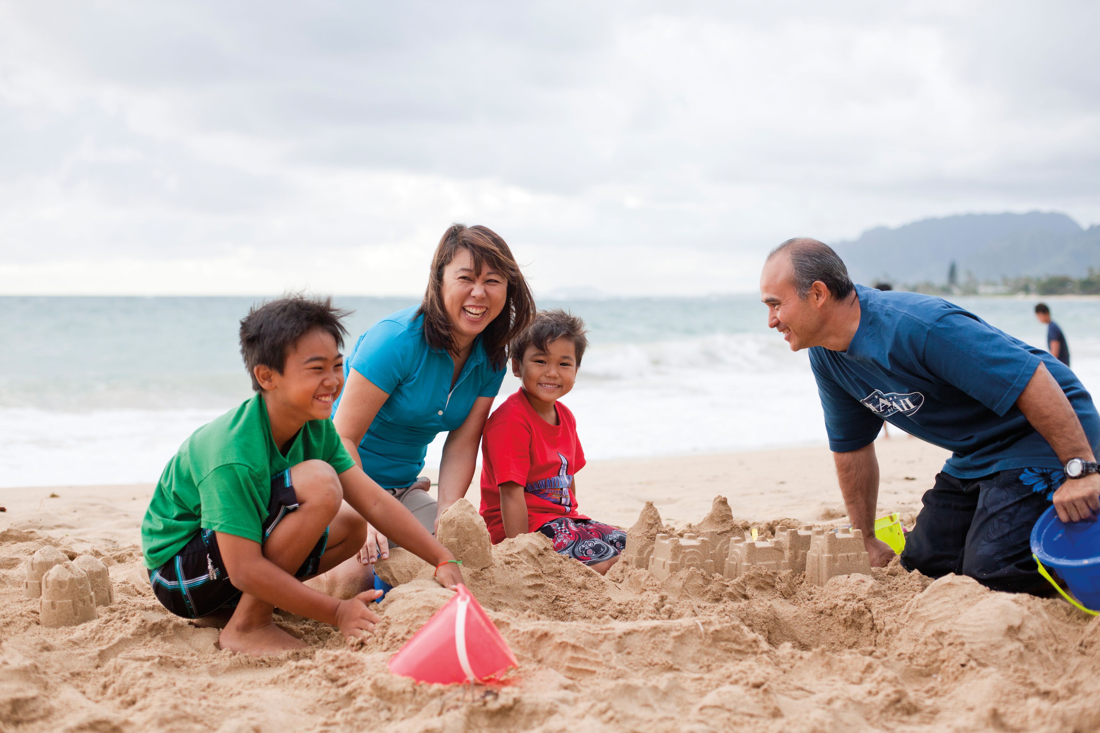A family builds a sand castle together.