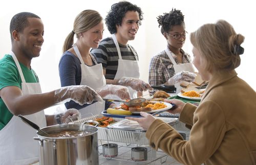 four people wearing white aprons serving food