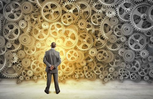 A man looking at a wall with different types of gears on it.