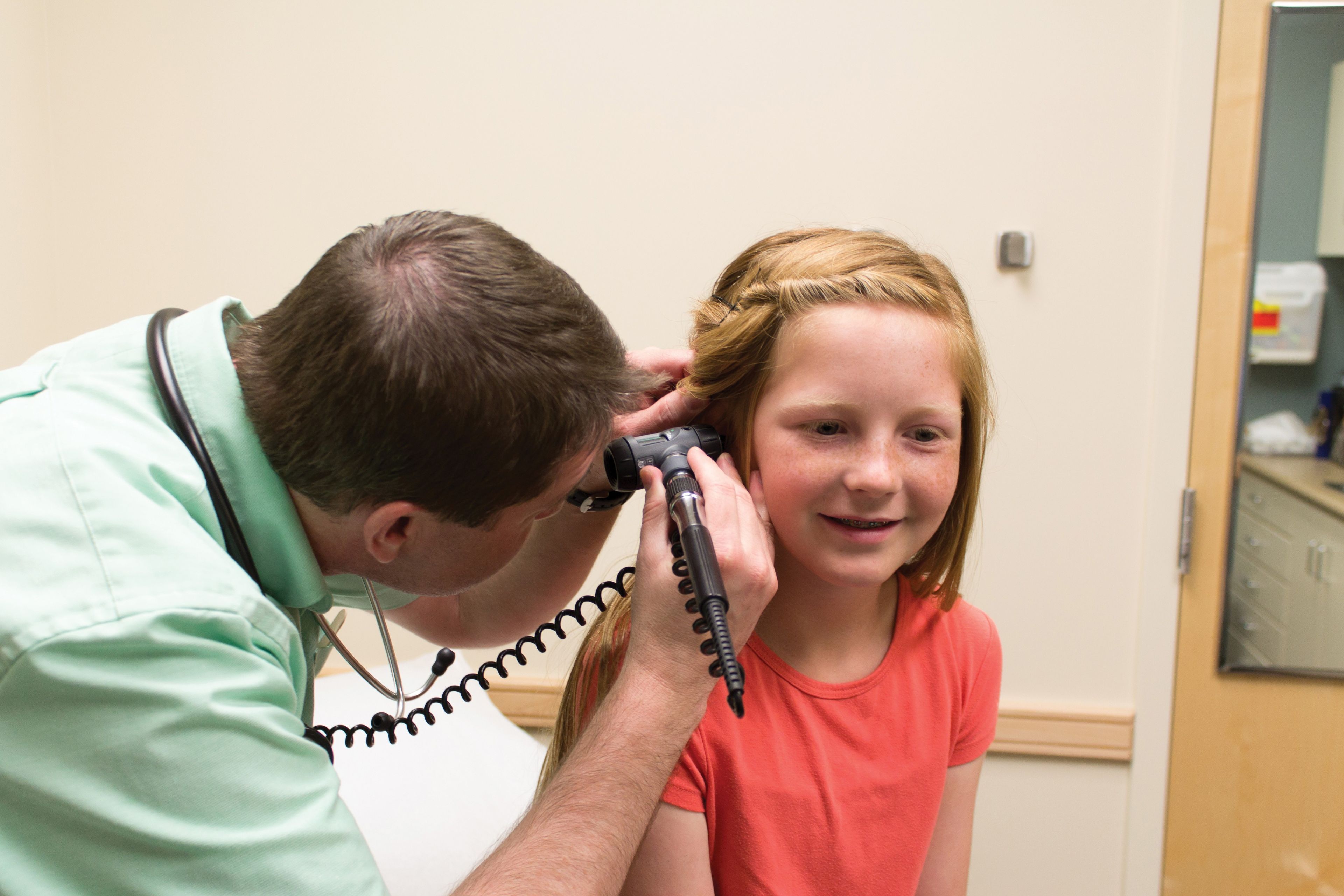 A doctor examining the ear of a young girl.
