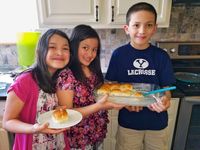 three children holding baked rolls