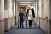 Boy with walker and woman walk down hallway