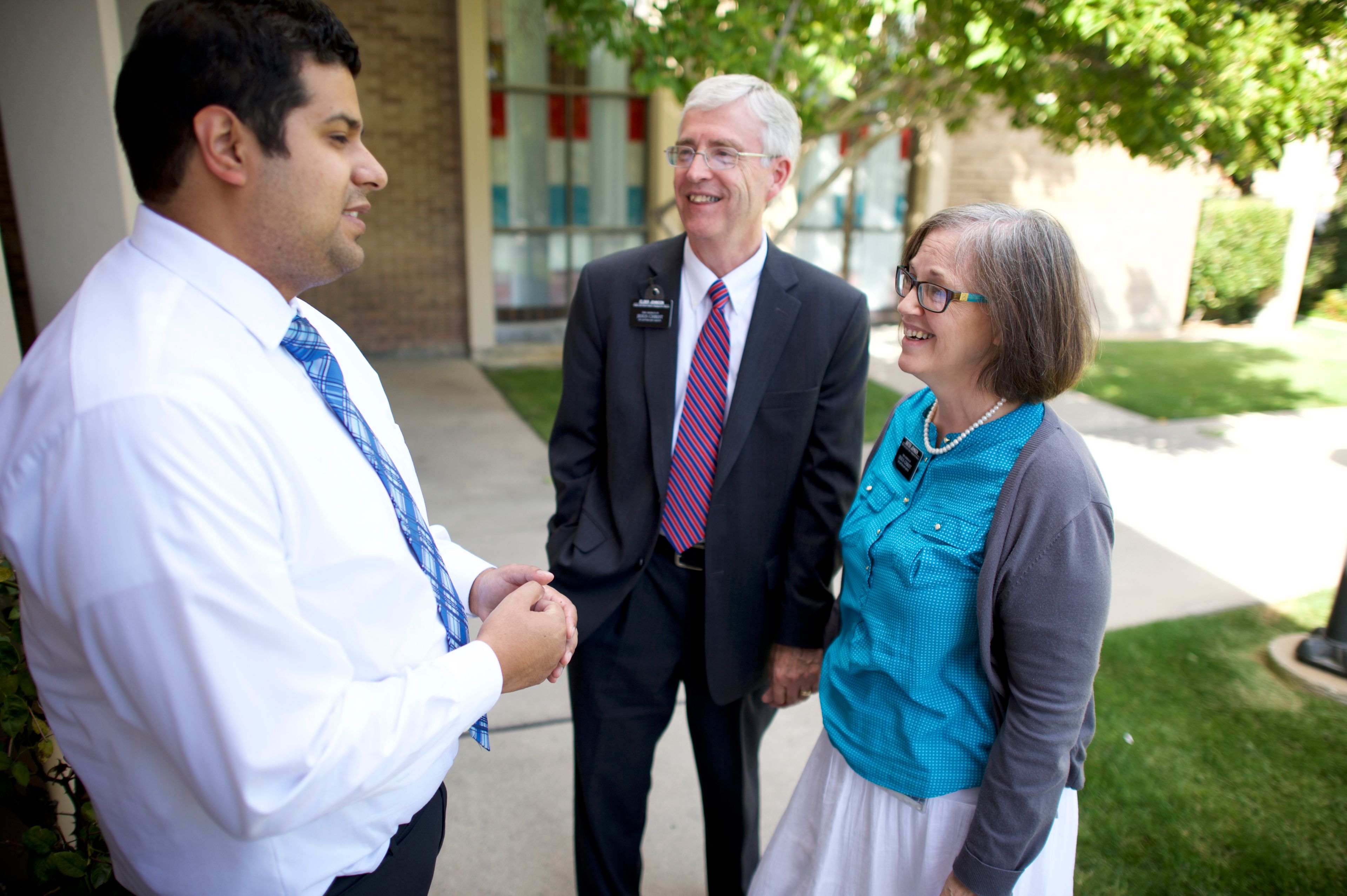A senior missionary couple standing and talking with a man.
