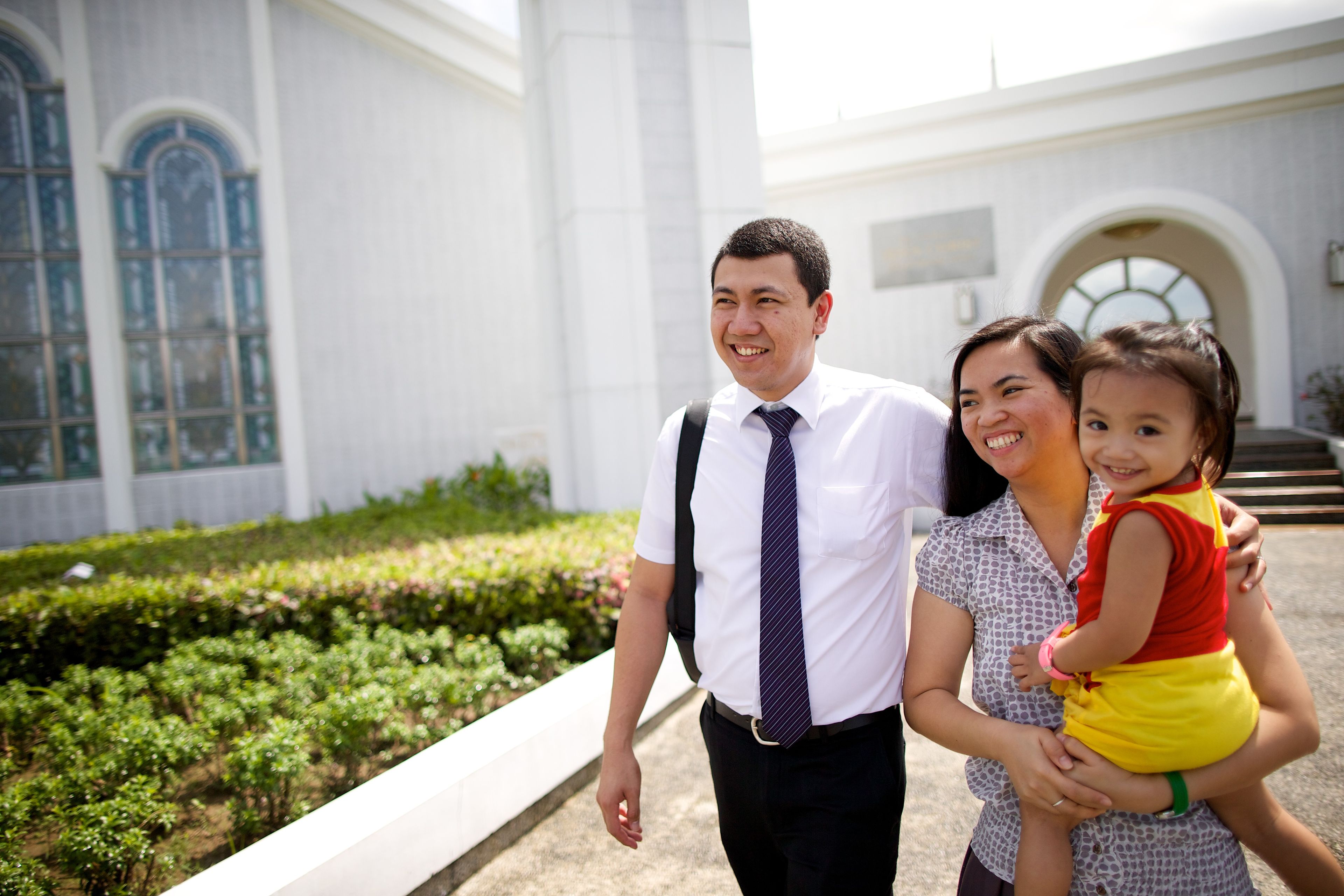 A couple and their young daughter walking outside the Manila Philippines Temple.
