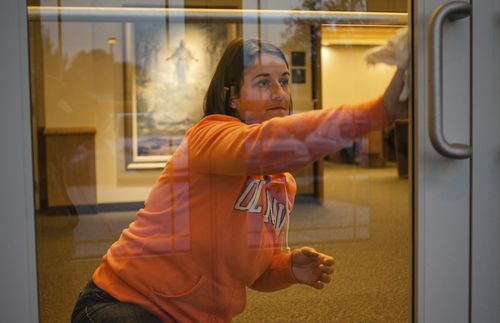 woman cleaning door to the chapel