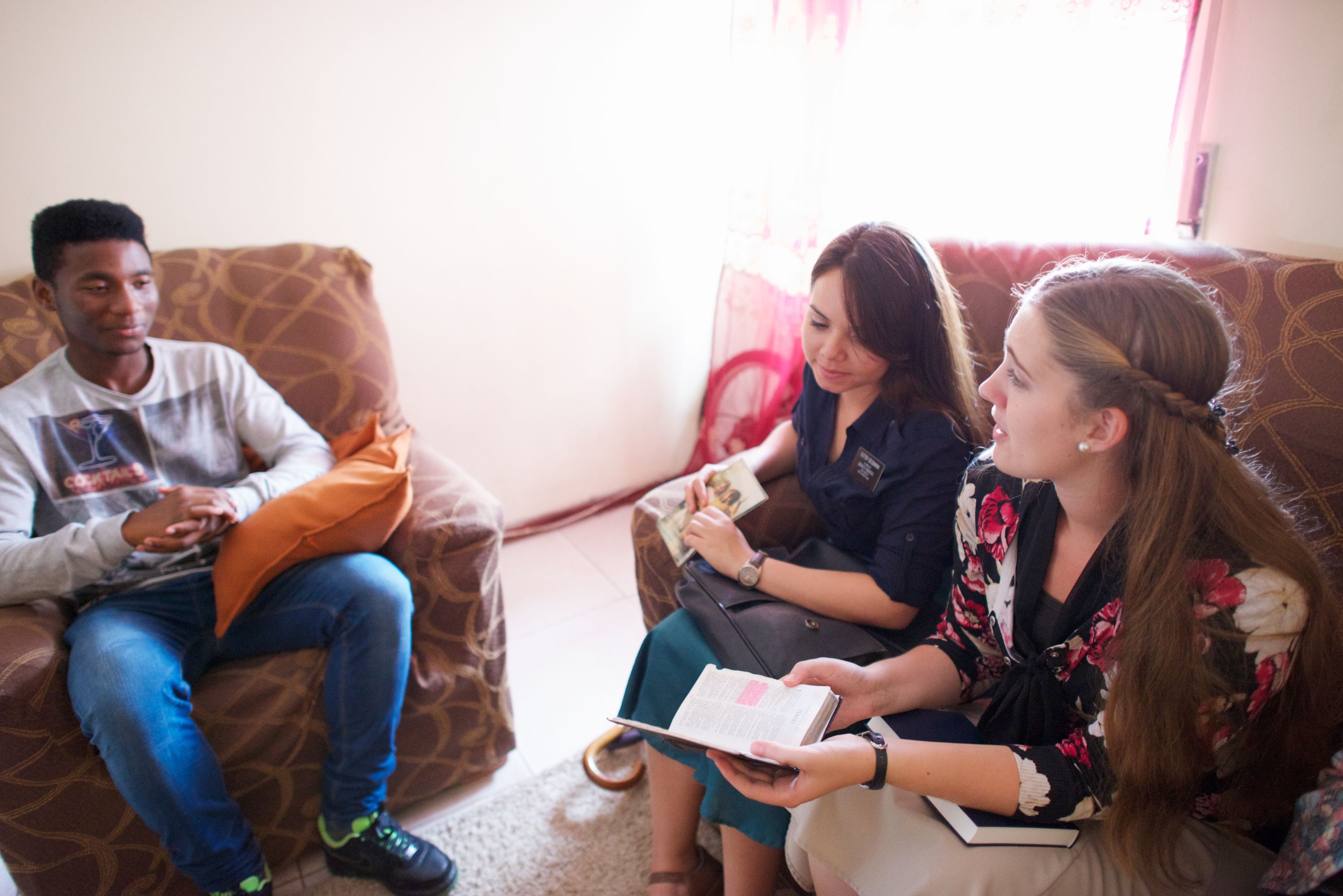 Sister missionaries teaching a young man in his home in Portugal.