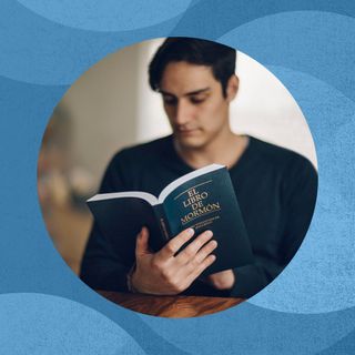 Man holding a blue softback Book of Mormon.