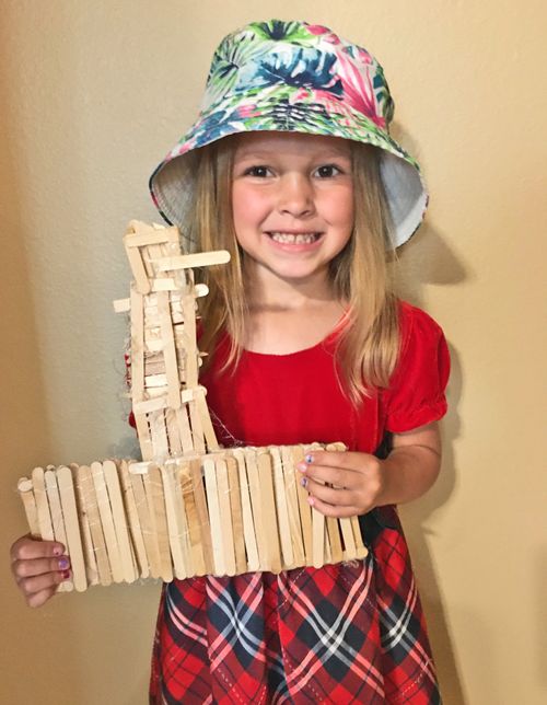 Girl with model of temple made with wooden craft sticks