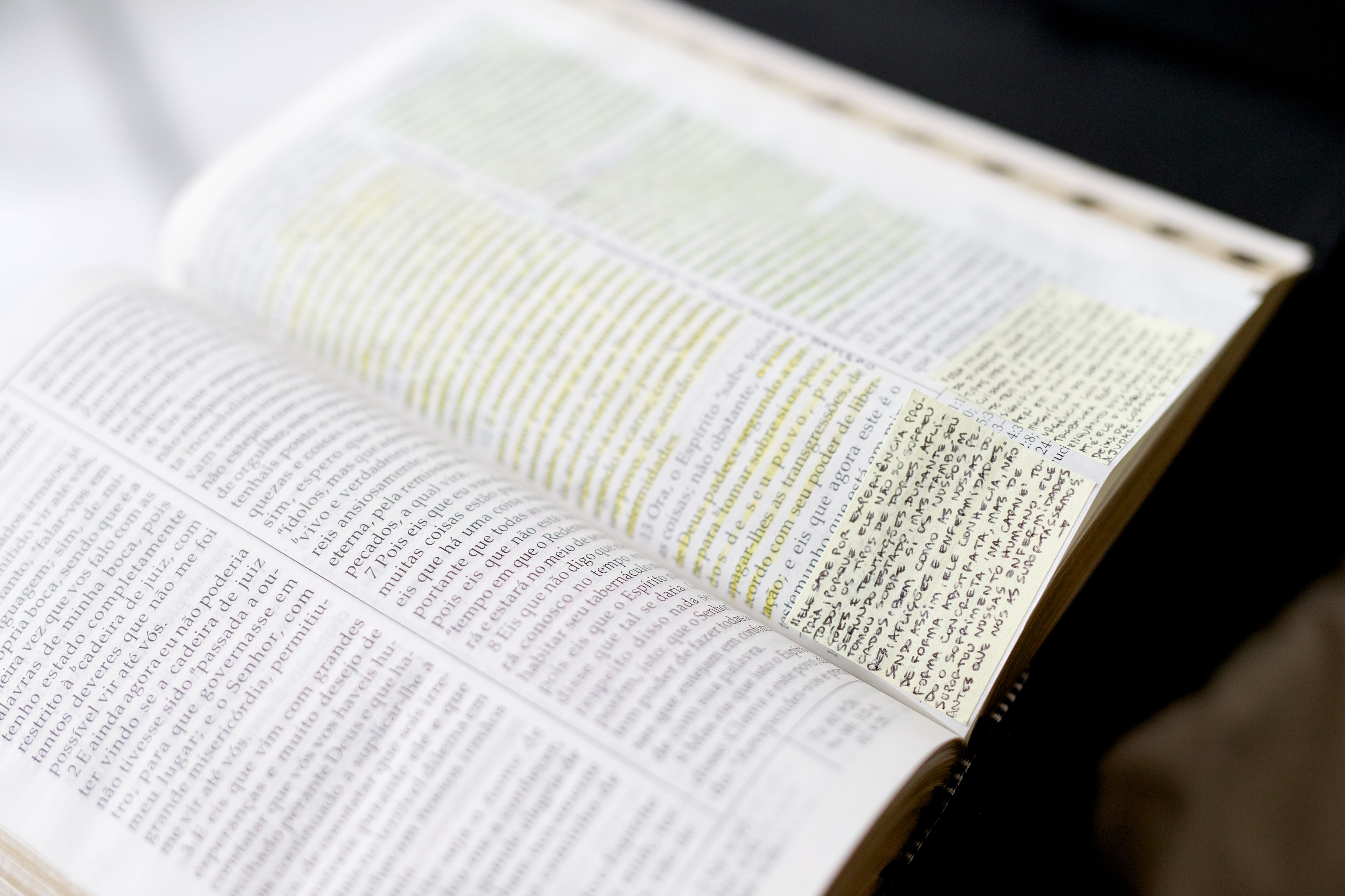 Opened Portuguese scriptures with yellow highlights and sticky notes.