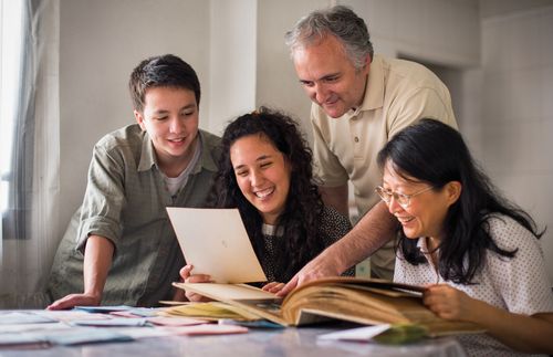 Family members together at a table looking at a photo album.